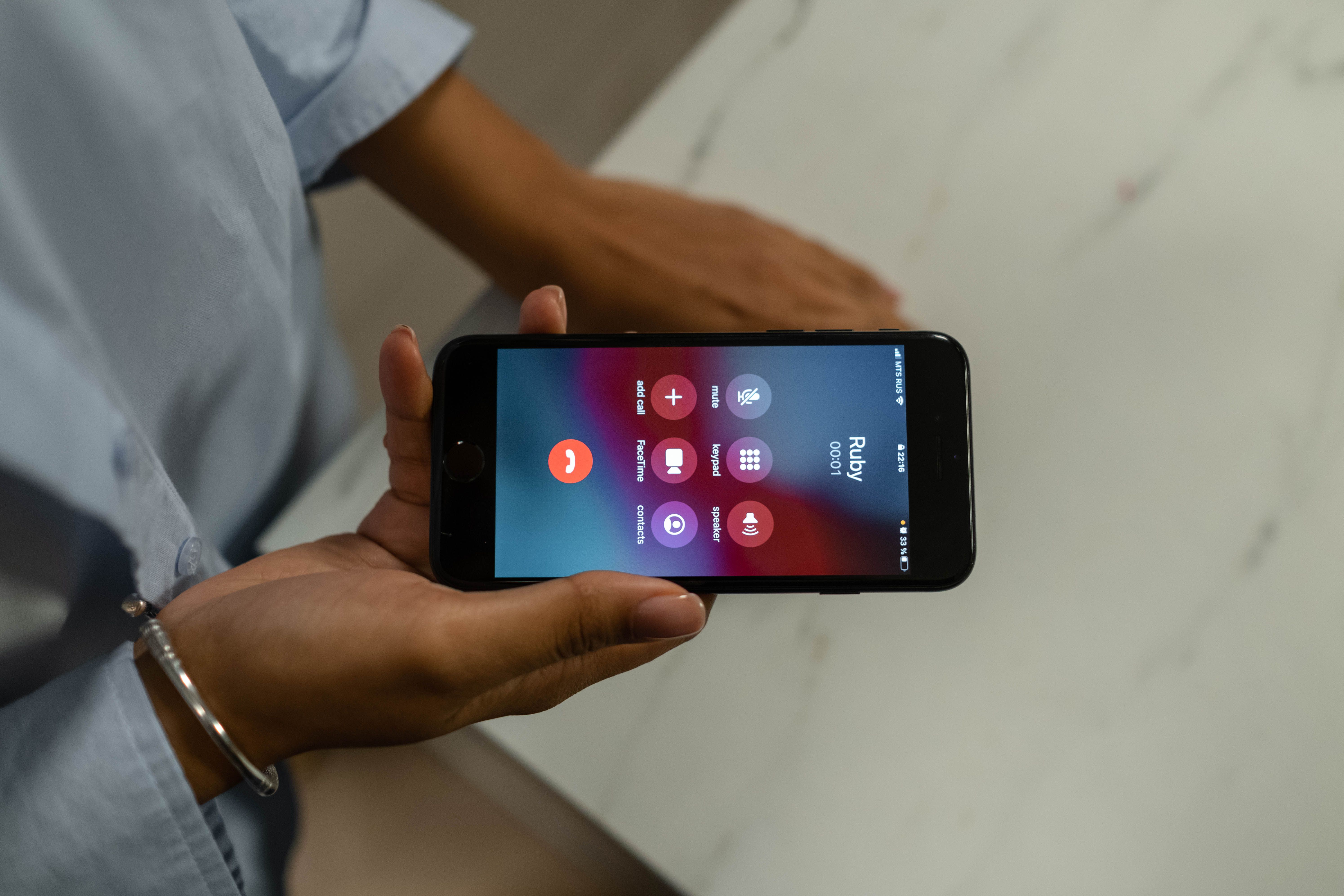 Mano sosteniendo un teléfono celular con una llamada entrante en la pantalla