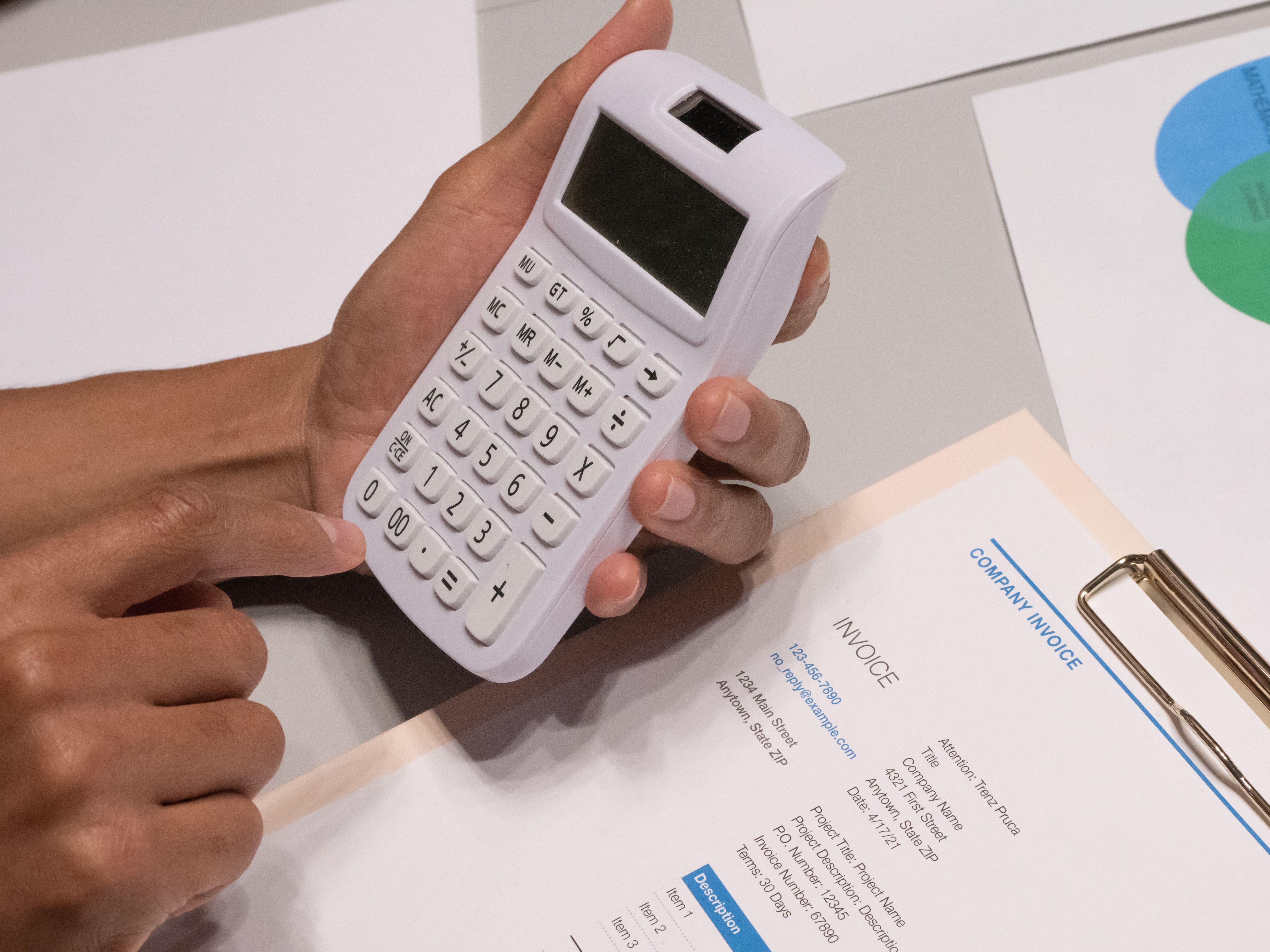 Manos usando una calculadora blanca sobre una factura, en un escritorio de oficina