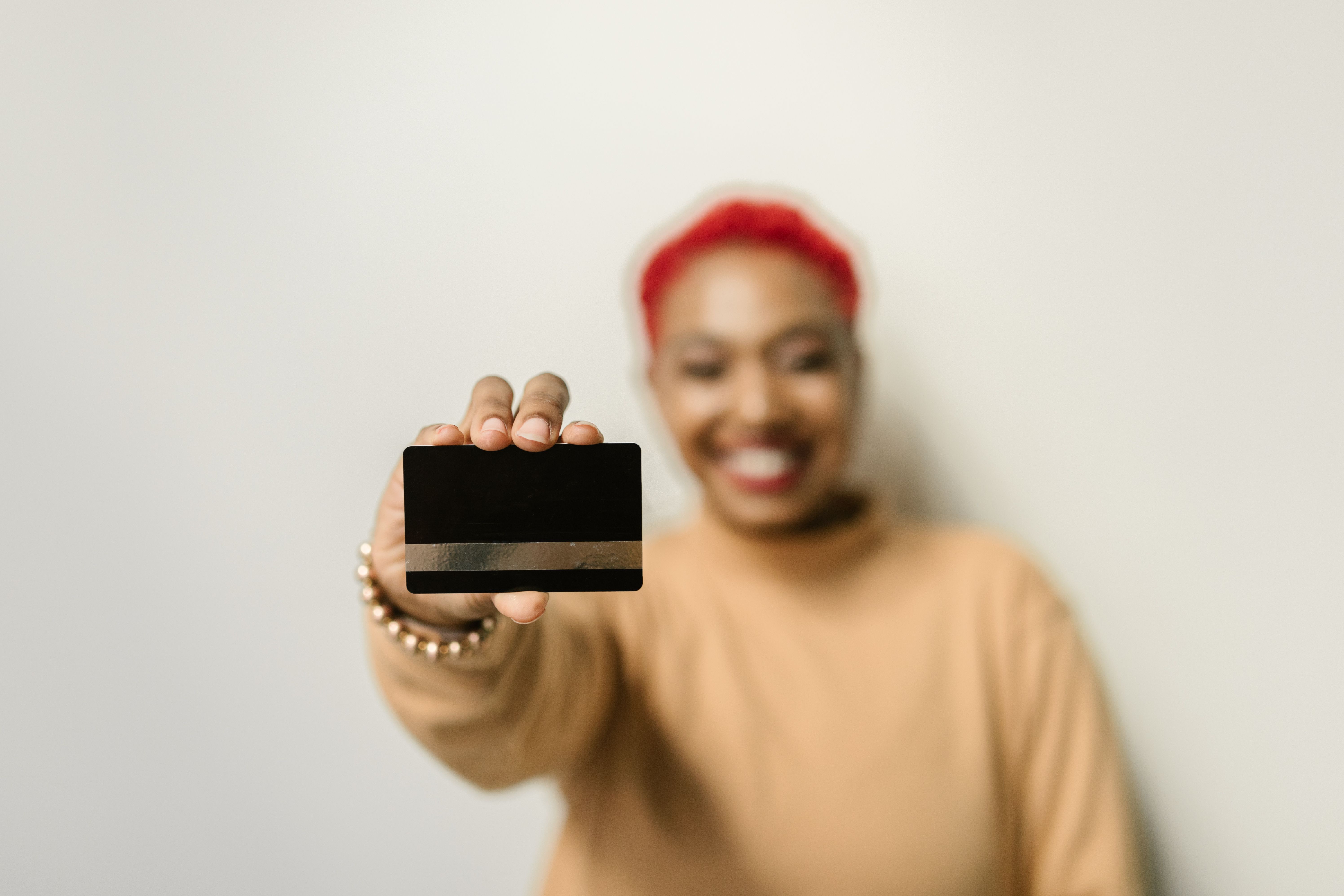 Persona sonriendo mientras sostiene una tarjeta de crédito en blanco, sin logo de banco visible