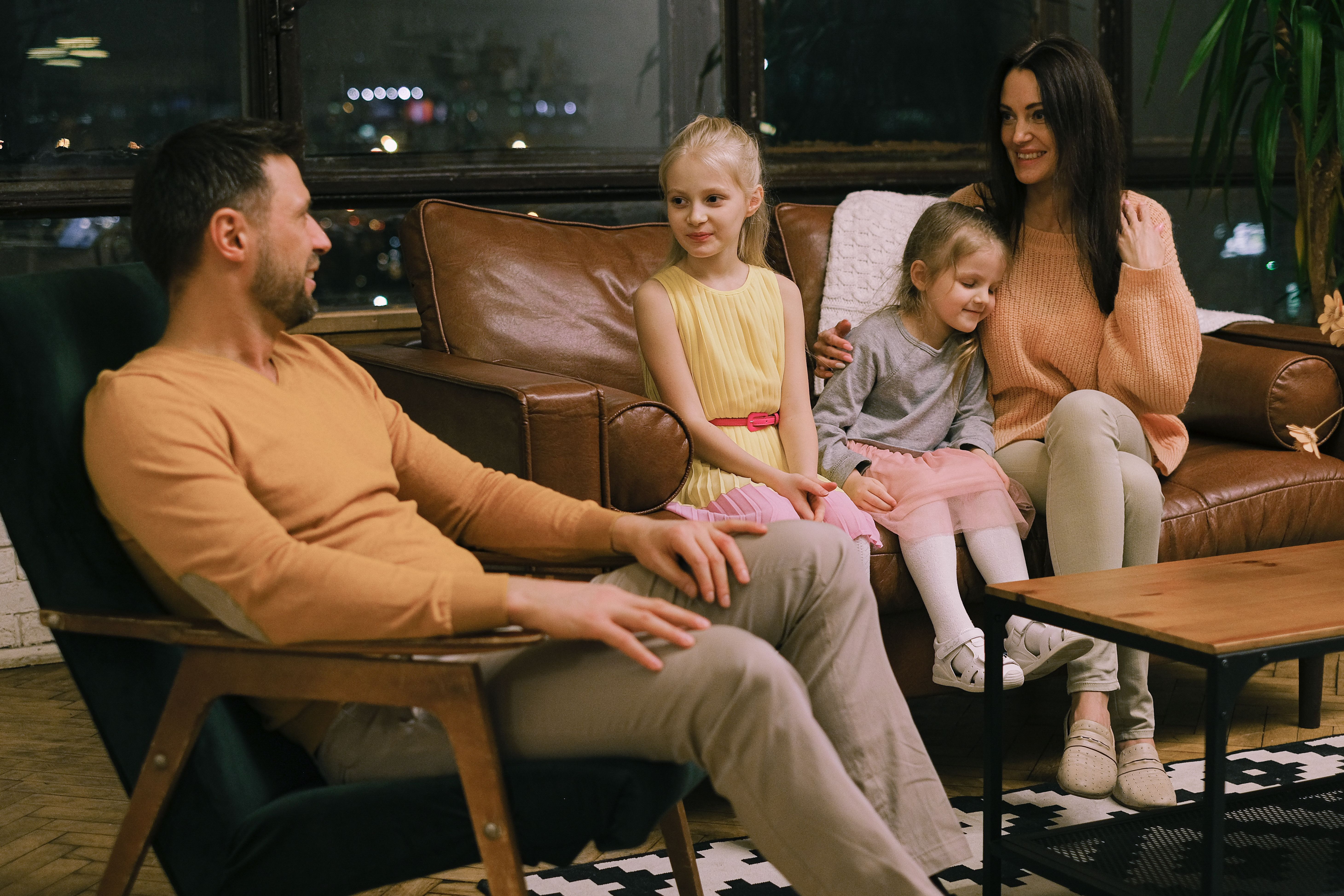 Familia de cuatro personas reunida y conversando en la sala de su casa