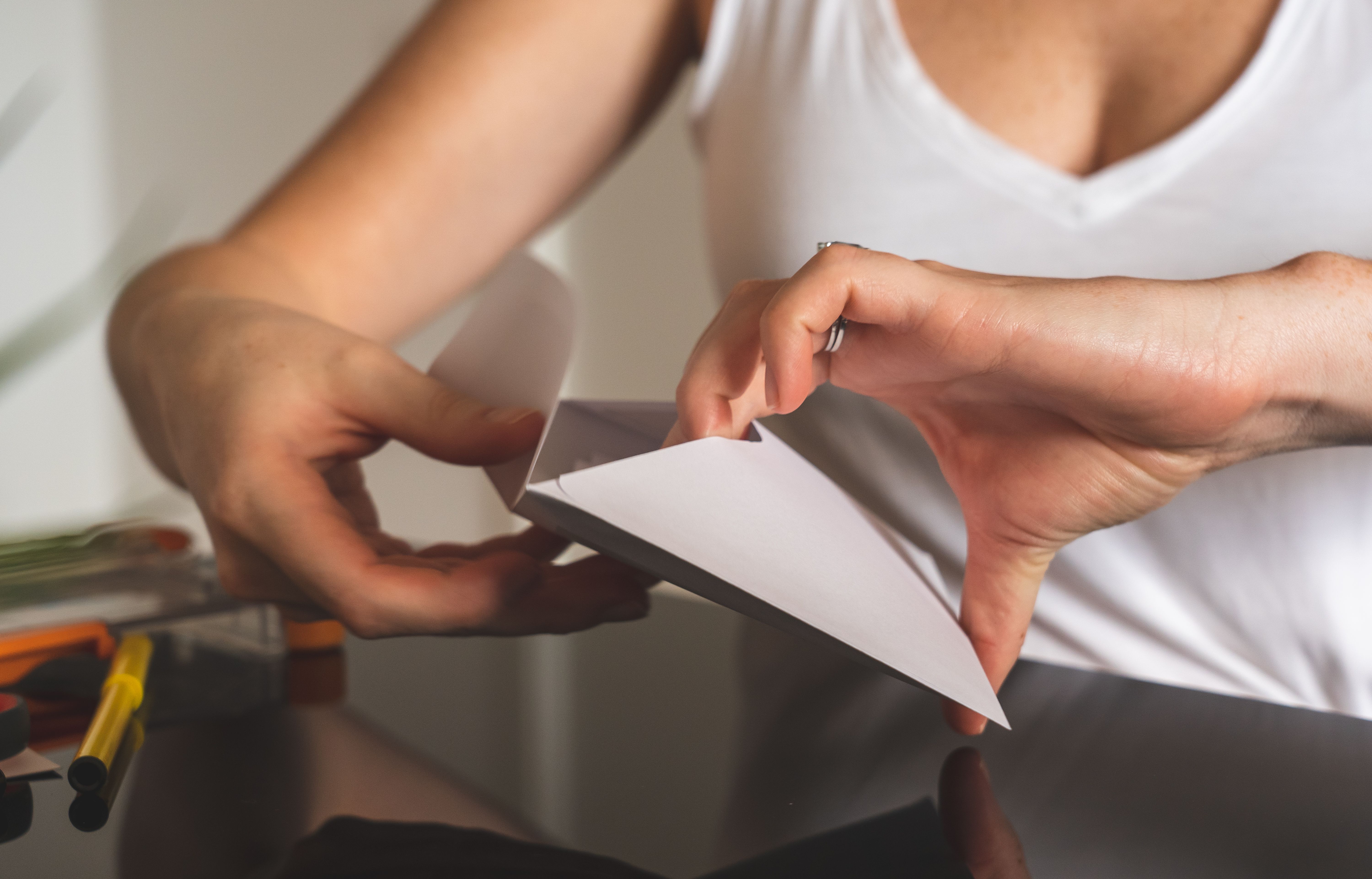 Primer plano de manos sellando un sobre blanco, relacionado con correspondencia y avisos por correo